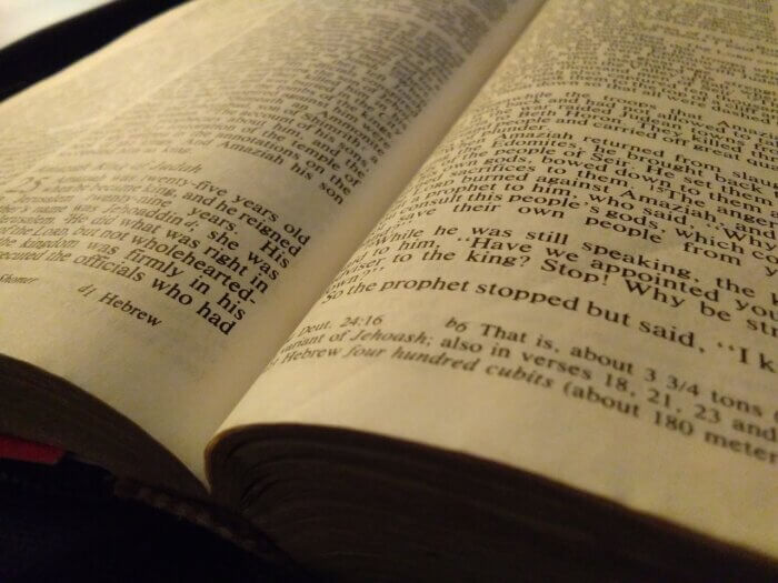 an open bible showing black lettered text on white pages
