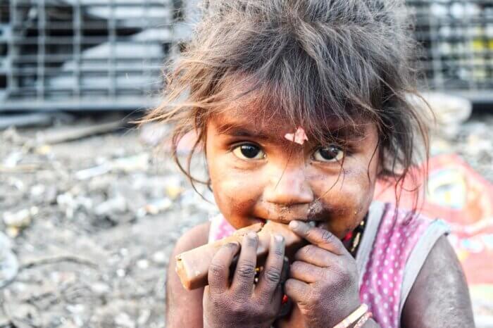 hungry, sad little girl eating a dry cracker in a dry setting