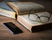 Open book on desk with glasses and phone