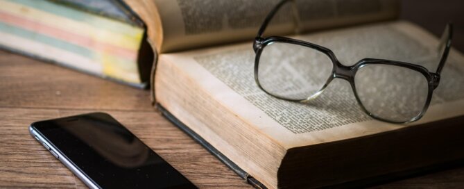 Open book on desk with glasses and phone